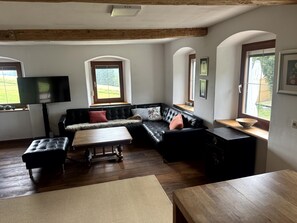 Una sala de estar moderna con un sofá modular, una mesa de centro de madera y un televisor montado en la pared.