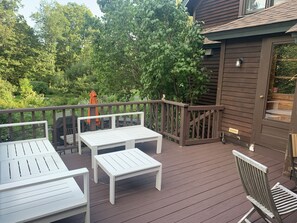 Une terrasse en bois avec des meubles blancs, notamment un banc et une table.