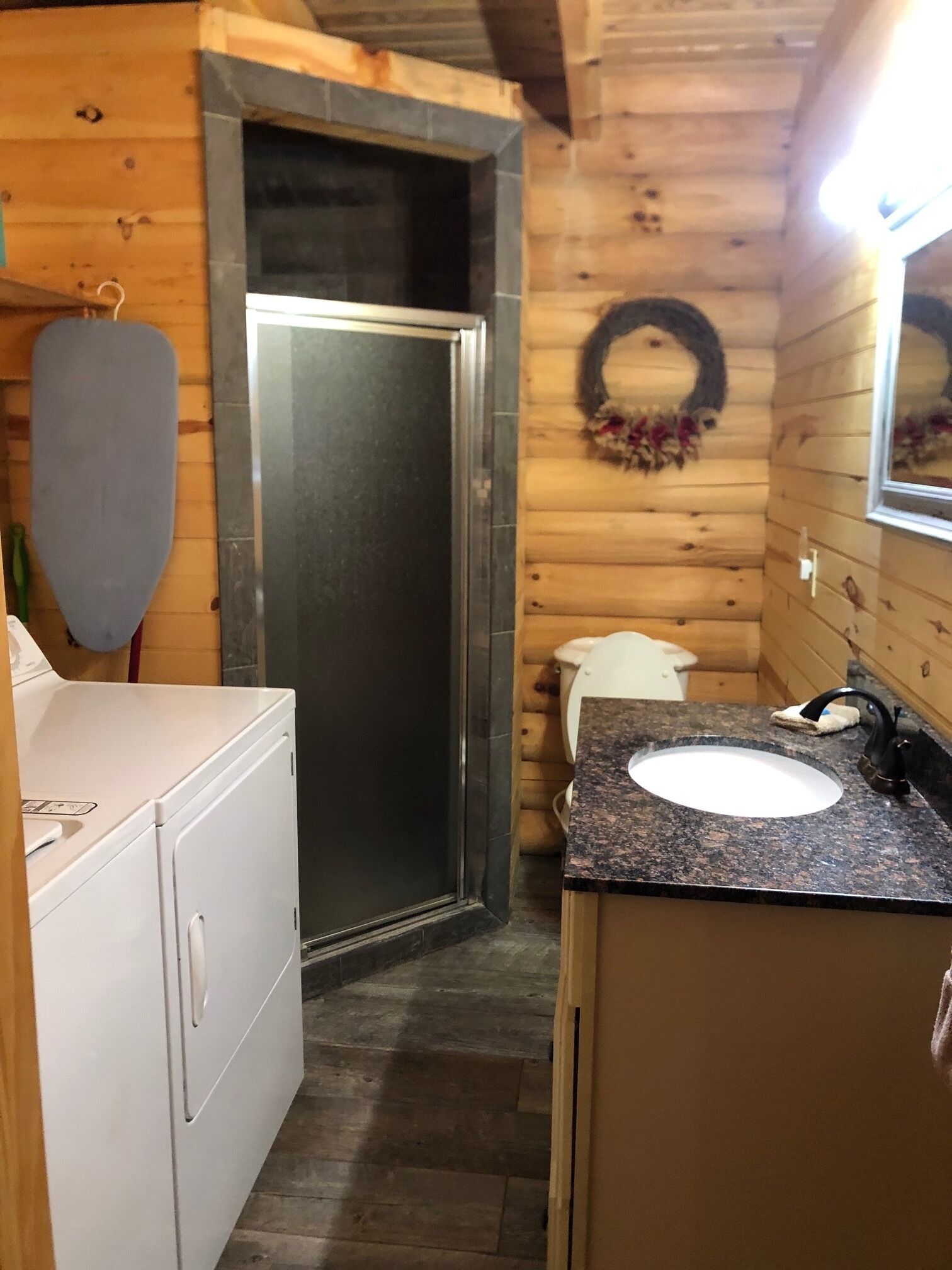 Ein kleines Badezimmer mit Holzausstattung, einem weißen Waschbecken und einer Duschkabine.