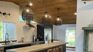 Una cocina moderna con una isla grande, luces colgantes y suelo de madera.