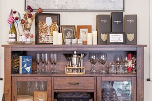 Un meuble en bois contenant des verres à vin, une bouteille de vin et une photo encadrée.