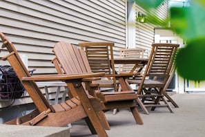 Outdoor wooden furniture including chairs and a table, positioned on a concrete surface.
