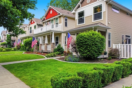 A row of townhouses with front porches, American flags, and well-maintained lawns.. Cozy & Modern Coeur d’Alene Retreat: Perfect for Families, Friends, and Pets