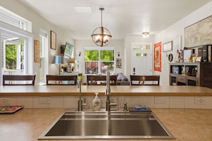 A modern kitchen with a central island, stainless steel sink, and a pendant light.