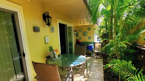A patio area with a glass table, chairs, and a door leading to an interior space.