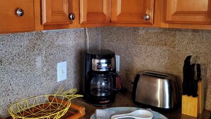 A kitchen with wooden cabinets, a coffee maker, a toaster, a knife block, and a woven basket.