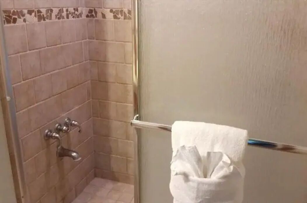 A bathroom with a shower, a towel rack, and a toilet paper holder.