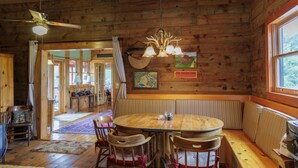 A wooden cabin interior with a round dining table, wooden chairs, a bench, and a ceiling fan. - The Lodge at Joe Walker Hollow, privacy at its best with plenty of family space (Middlebrook)