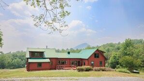 A log cabin with a green roof, a porch, and a mountain in the background. - The Lodge at Joe Walker Hollow, privacy at its best with plenty of family space (Middlebrook)