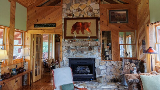 A cozy lodge interior with a stone fireplace, wooden beams, and a bear painting. - The Lodge at Joe Walker Hollow, privacy at its best with plenty of family space (Middlebrook)