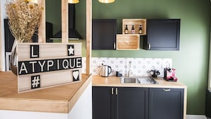 A kitchen with black cabinets, a wooden countertop, and a decorative block spelling out "L AT Y P I Q U E #".
