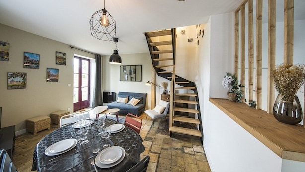 A modern living space with a dining area, a staircase, and a kitchen.