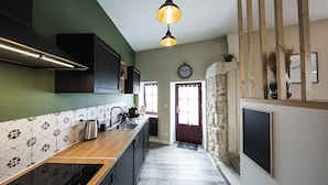 A modern kitchen with a wooden countertop, a built-in oven, and a black range hood.