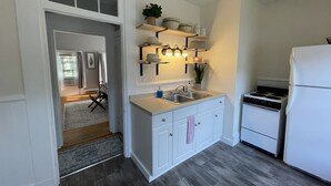 Une cuisine moderne avec des meubles blancs, un évier en acier inoxydable, une cuisinière encastrée et un éclairage au plafond.