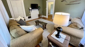 Un salon avec un canapé, une table basse, une lampe et un téléviseur.