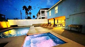 Una piscina con fuente, sillas de descanso y un edificio con balcón.