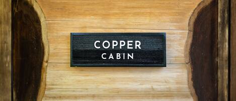 A wooden cabin with a sign that reads "COPPER CABIN."