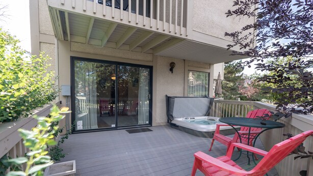 A covered patio with a hot tub, outdoor seating, and a sliding glass door leading to an interior space.