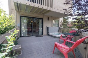 Un patio couvert avec un jacuzzi, des sièges d’extérieur et une porte-fenêtre coulissante donnant sur un espace intérieur.