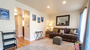 A living room with a brown sofa, a patterned rug, a small table, and a cart.