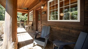 A wooden cabin with a porch, two Adirondack chairs, a grill, and a sign reading "Halfmoon Cottage." - Halfmoon Cottage I Nature Escape I Hot Tub I Pets (Ucluelet)