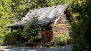 A rustic cabin with a sloped roof, surrounded by dense greenery. - Halfmoon Cottage I Nature Escape I Hot Tub I Pets (Ucluelet)