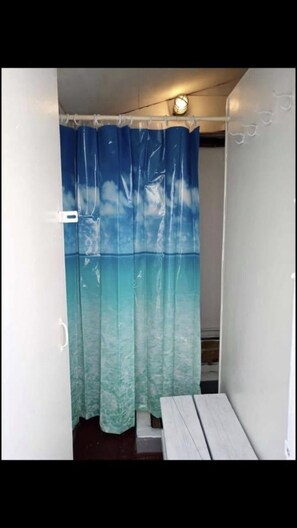 A bathroom with a blue and green gradient shower curtain, a white wall, and a small wooden bench. - Steps to the beach (Seaside Park)