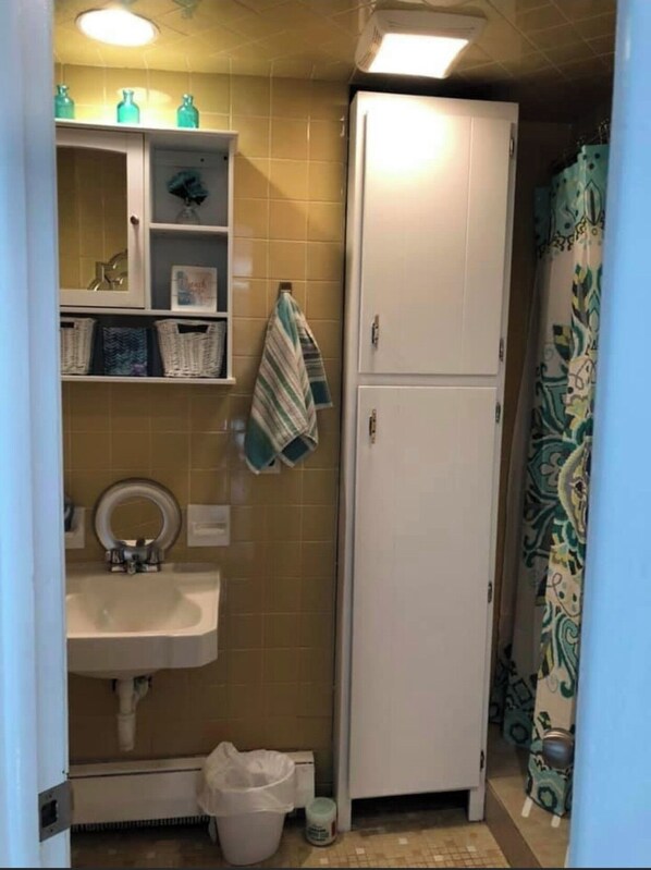 A compact bathroom with a sink, mirror, and a white cabinet. - Steps to the beach (Seaside Park)