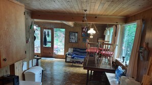 A rustic cabin interior with a kitchen, dining area, and a cozy living room. - Cottage with 40' Dock!  Beautiful lake with excellent fishing. (Port loring)