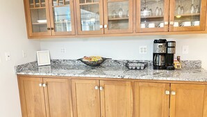 A kitchen with wooden cabinets, a marble countertop, a coffee maker, and a bowl of cereal. - LAKE HOME! HOT TUB, GYM, FREEgolf cart, 2 kitchens (East Waterboro Maine)