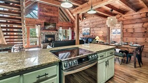A spacious kitchen with granite countertops, a built-in stove, and a dining area with a long table set for six.