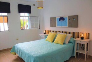 Ein Schlafzimmer mit einem Bett, Nachttischen, einem an der Wand montierten Fernseher und Kunstwerken.