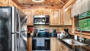 Een moderne keuken met roestvrijstalen apparatuur, houten keukenkastjes en een zwart granieten aanrecht.