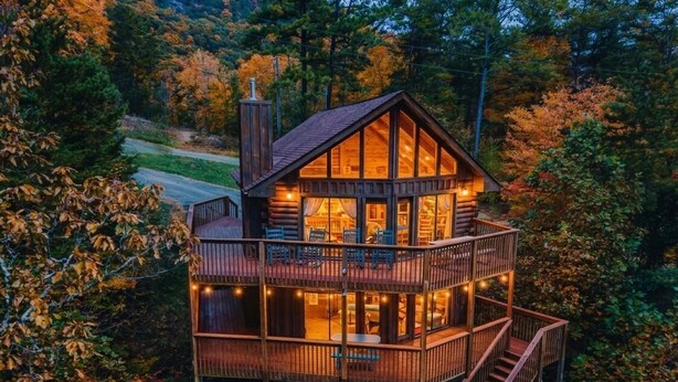 Een meerlaags blokhut met balkon, jacuzzi en wenteltrap.