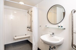 Ein modernes Badezimmer mit Dusche, Waschbecken, Spiegel und einer Glasablage für Pflegeprodukte.