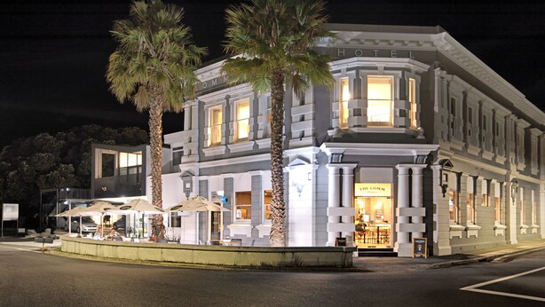 A hotel with a classic facade, palm trees, and outdoor seating.