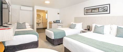 Een hotelkamer met twee bedden, een bureau met televisie, een badkamer en een lijst aan de muur.