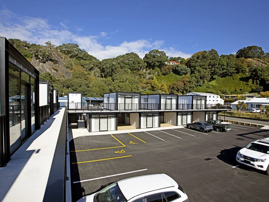 A modern building with a parking lot, a white car, and a truck.