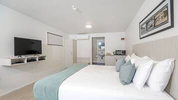 Ein modernes Hotelzimmer mit einem großen Bett, einem Flachbildfernseher, einer Mikrowelle und einer kleinen Küchenzeile.