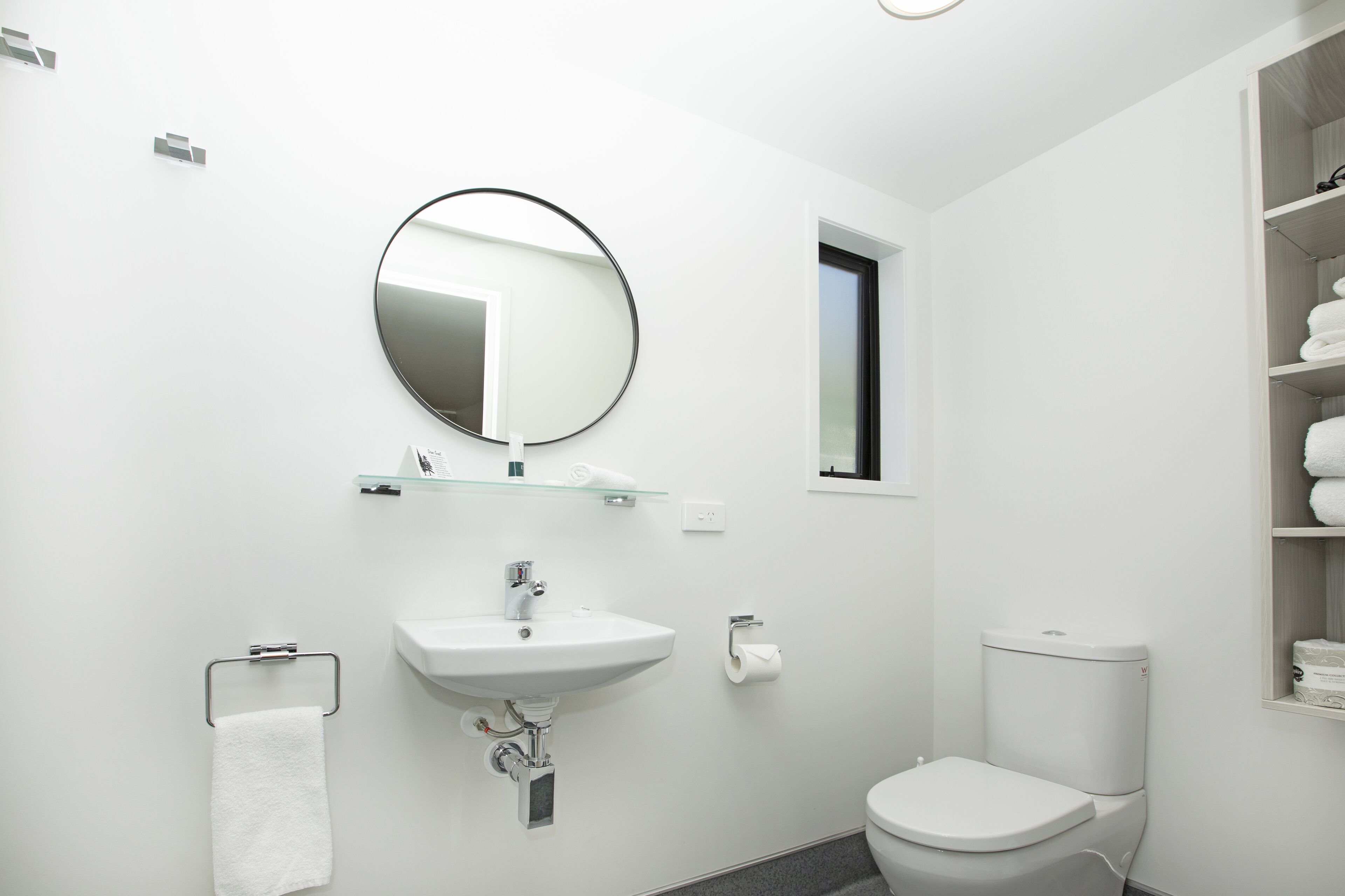 Une salle de bain moderne avec un lavabo blanc, un miroir et des toilettes.