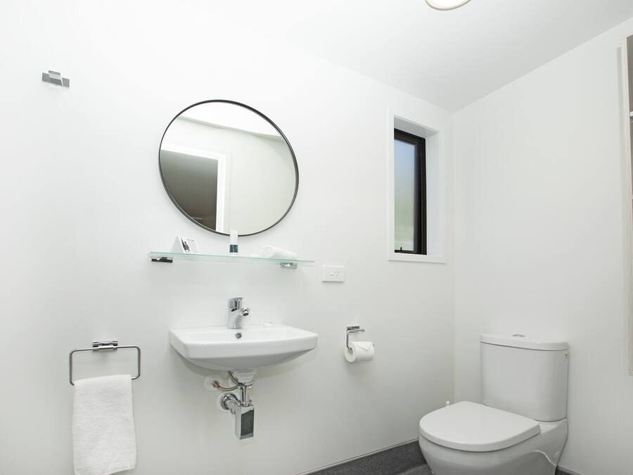 Une salle de bain moderne avec un lavabo blanc, un miroir et des toilettes.