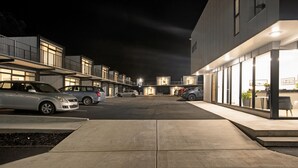 A modern building with a parking lot and several parked cars.