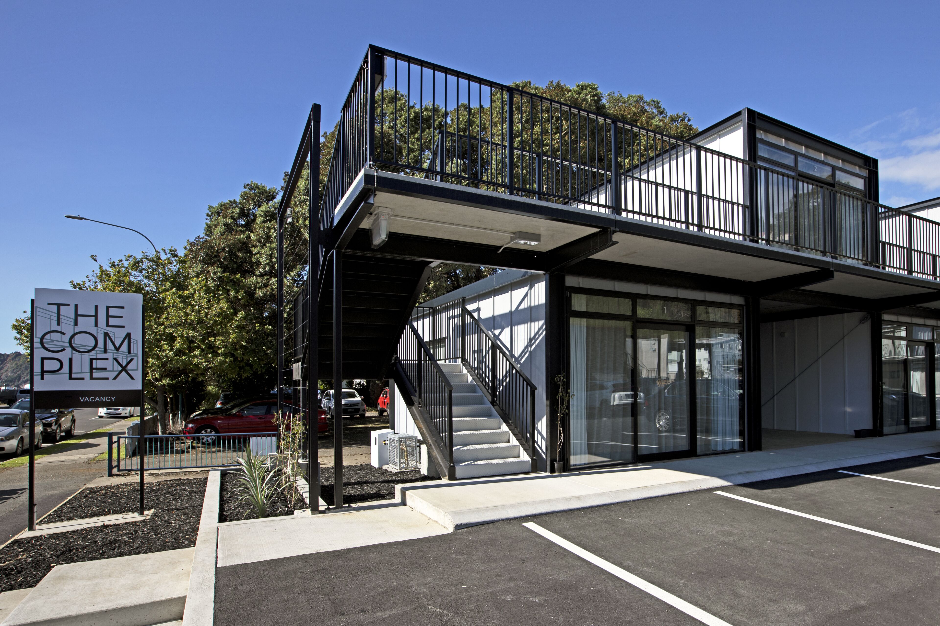 A modern building with a sign reading "THE COMPLEX" indicating a vacancy.