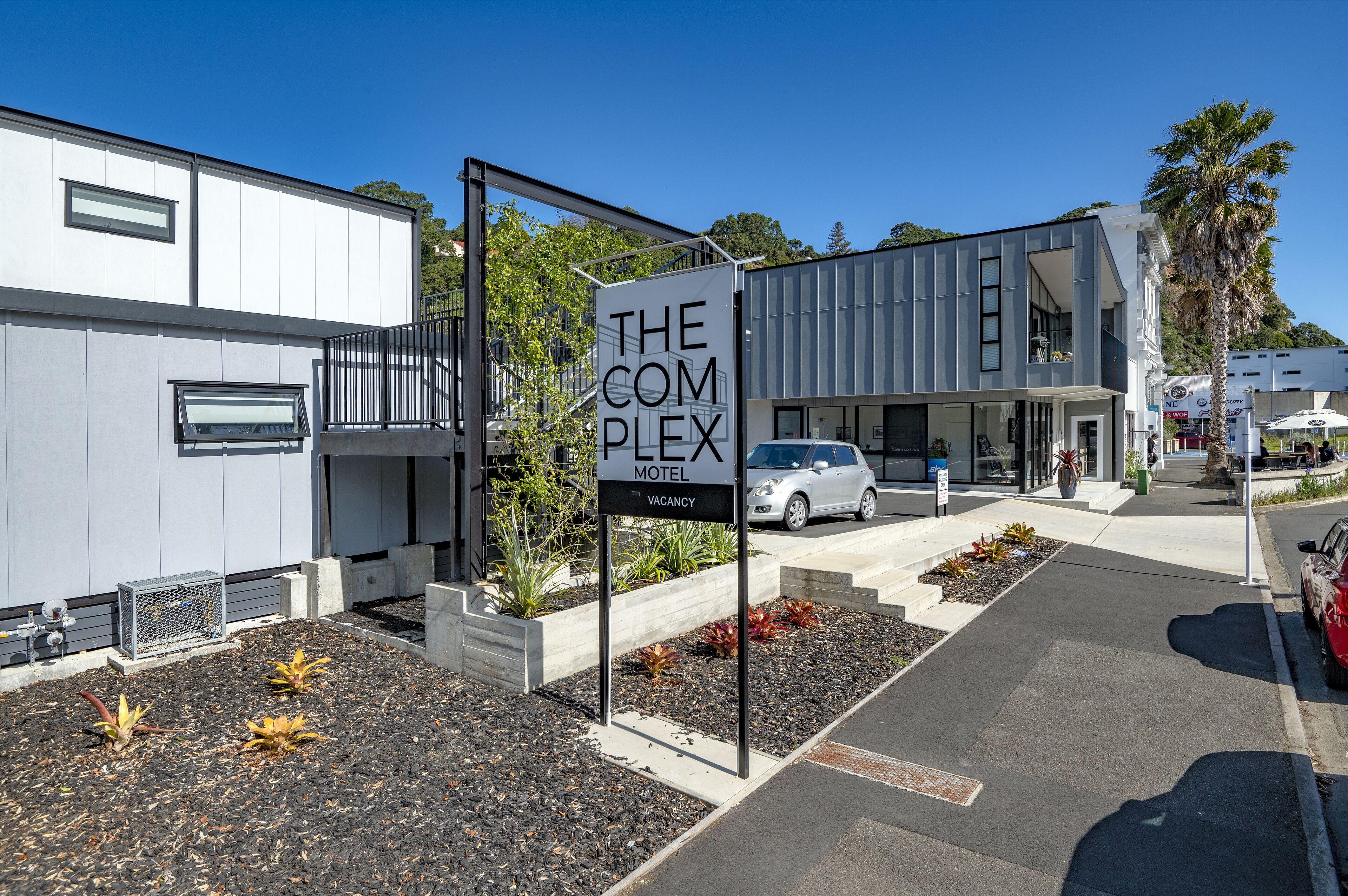 A modern building with a sign for 'The Complex Motel' indicating a vacancy.