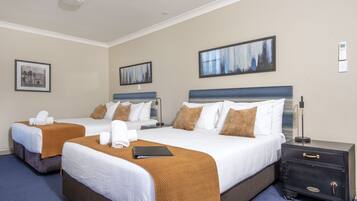 Une chambre d’hôtel avec deux lits, une table de chevet et une lampe fixée au mur.