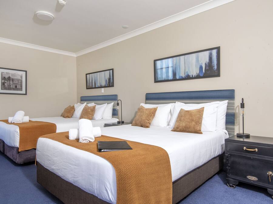 Une chambre d’hôtel avec deux lits, une table de chevet et une lampe fixée au mur.