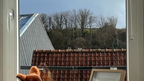 Una finestra con vista su un tetto in tegole, un giocattolo di peluche e una cornice con un'immagine sul davanzale.