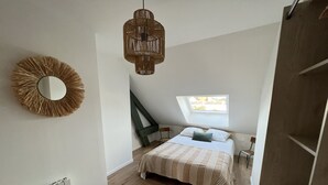 Una camera da letto con un letto, un lucernario, un lampadario, un termosifone e uno specchio a parete.