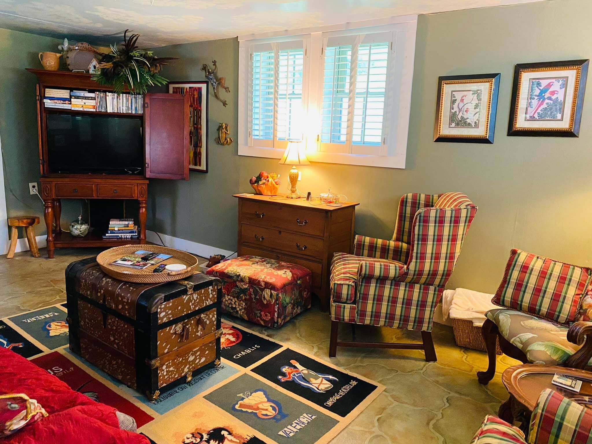 A cozy living room with a television, a plaid armchair, a wooden cabinet, and a coffee table with a placemat featuring cartoon characters.