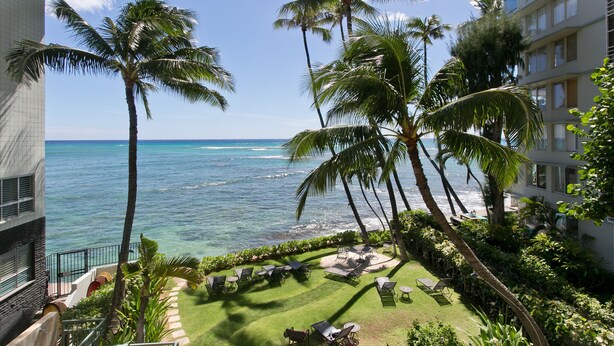 A hotel courtyard with a view of the ocean, palm trees, and outdoor seating area. - A Gem of a Studio at The Diamond Head Beach Hotel (Honolulu)
